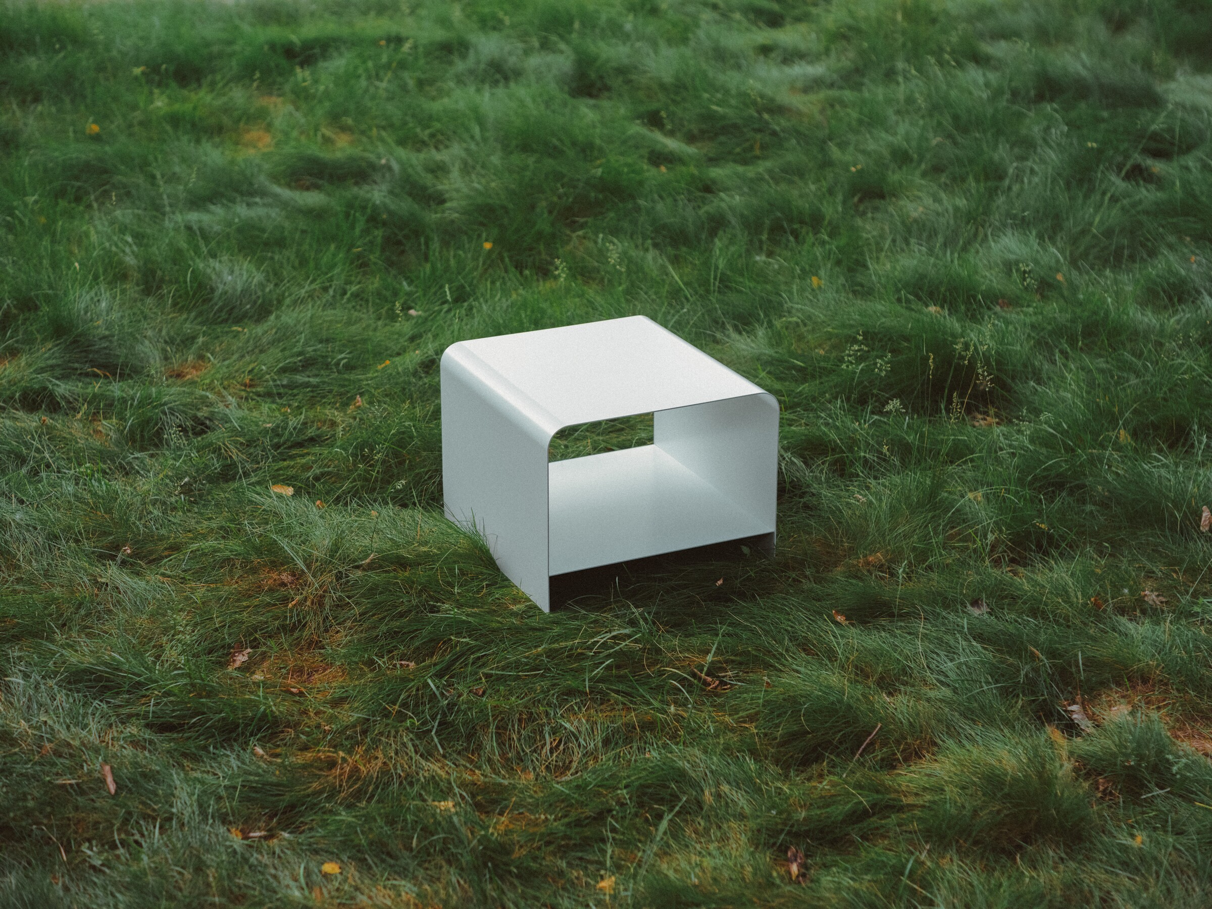 View of MEL's Radius Table in white outside amongst long grass